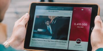 man wearing green long-sleeved shirt using iPad
